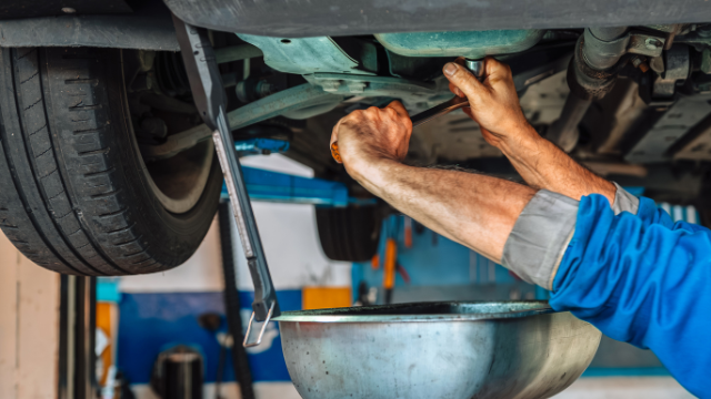 Car mechanic working underneath car