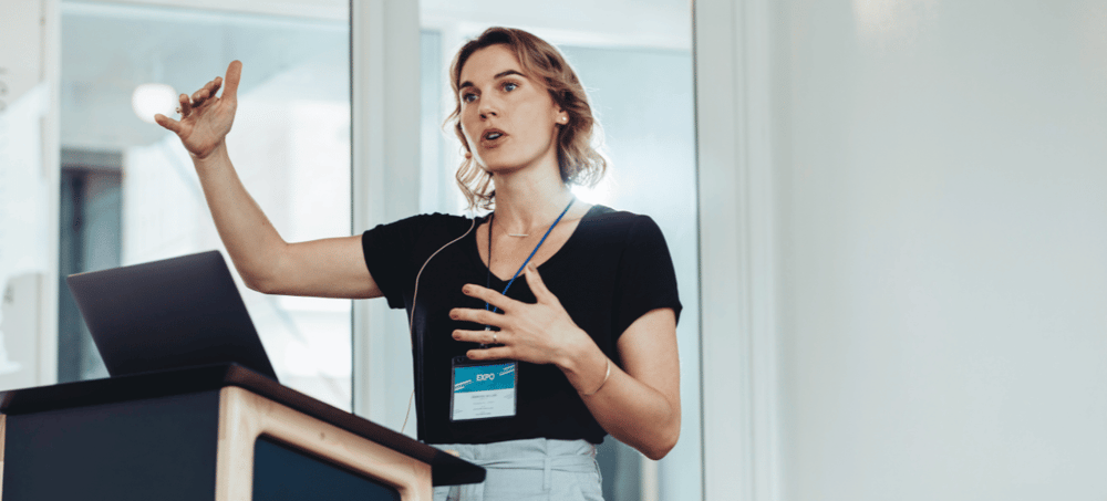 White female in black t-shirt giving a presentation