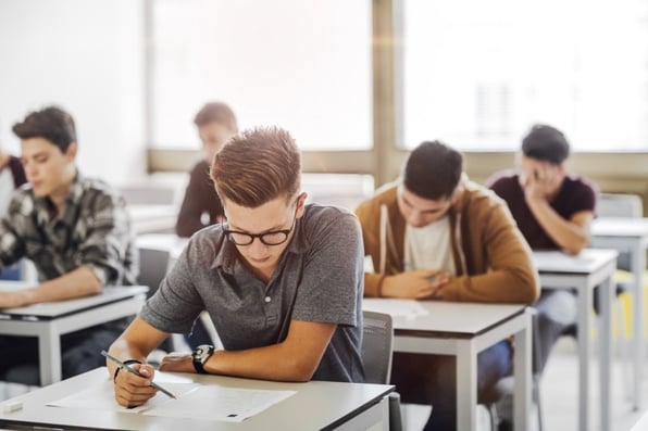 Children sit at desks in a classroom, working on an exam