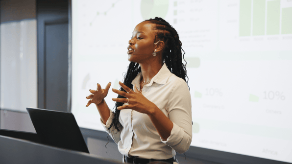Young black female standing up and speaking in front of an audience