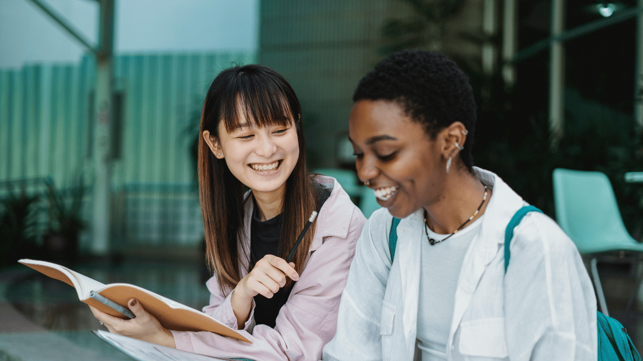 Two female students sitting together and smiling