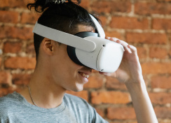 Man with VR headset on and brick background.