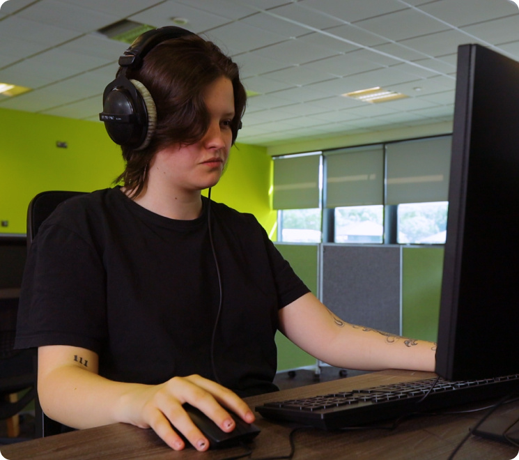 female student working on a computer in a computer lab with black hair and black clothes