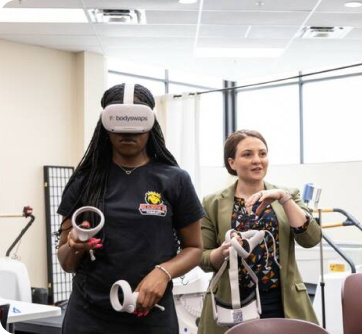 Two females with VR headsets. one using their headset and one talking.