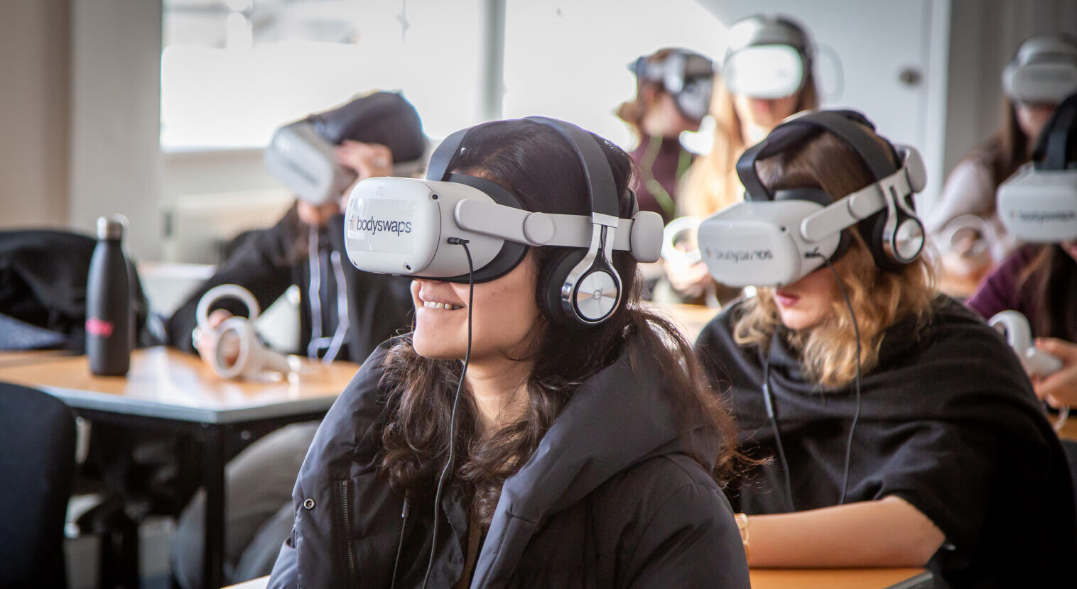 students in black hoodies, wearing Bodyswaps VR headsets, sitting in a classrom