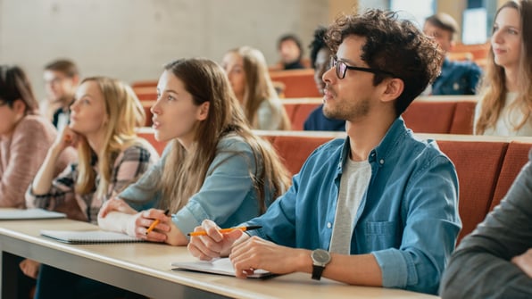 In the Classroom Multi Ethnic Students Listening to a Lecturer and Writing in Notebooks. 