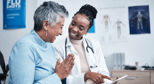 A female doctor discusses results with a female patient, both are smiling