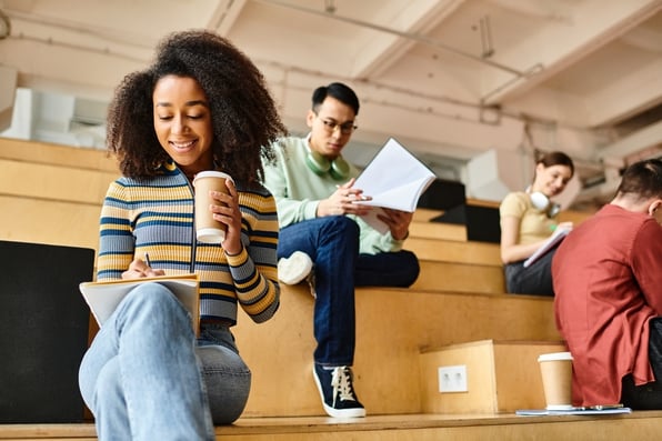 Students of various backgrounds reading notes in a university lecture hall setting.