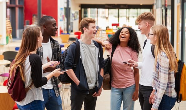 A group of students standing and chatting together in a university building