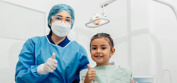 Child patient with female dentist both holding a thumbs up